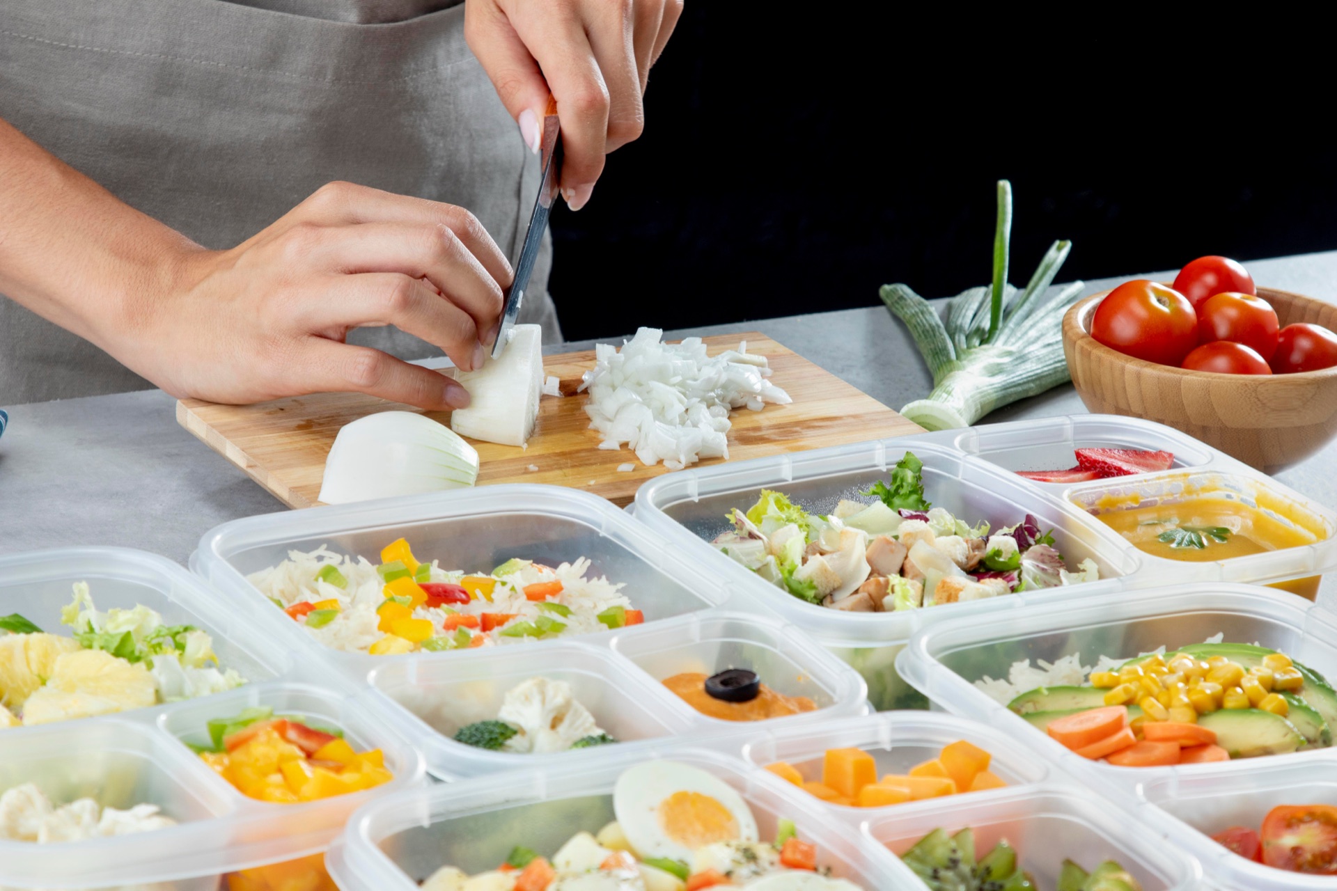 Hands portioning prepped food into labelled containers